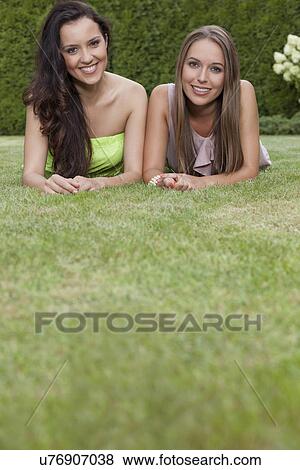 Portrait of attractive young female friends relaxing in park View Large Photo Image Stock Photo - Portrait of attractive young female friends relaxing in park. Fotosearch
