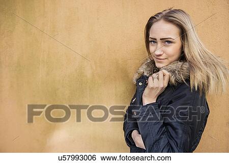 Portrait of beautiful teenage girl in jacket standing against wall View Large Photo Image Stock Photograph - Portrait of beautiful teenage girl in jacket standing against wall. Fotosearch