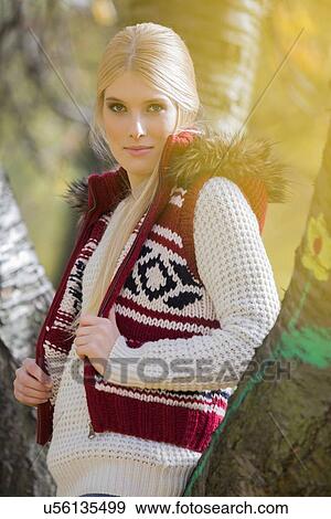 Stock Photo - Portrait of beautiful woman in warm clothing standing in park. Fotosearch