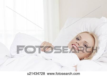 Stock Photo - Portrait of beautiful young woman lying in hotel room. Fotosearch