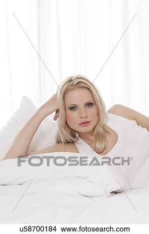 Picture - Portrait of beautiful young woman reclining in bed. Fotosearch