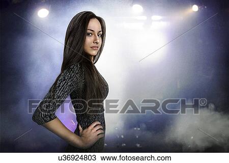 Stock Image - Portrait of beautiful young woman posing in nightclub. Fotosearch