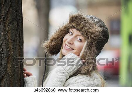 Stock Image - Portrait of beautiful young woman wearing fur hat outdoors. Fotosearch