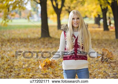 Portrait of beautiful young woman holding autumn leaves in park View Large Photo Image Stock Image - Portrait of beautiful young woman holding autumn leaves in park. Fotosearch