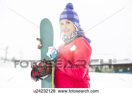 Portrait of beautiful young woman holding snowboard in snow View Large Photo Image Stock Photo - Portrait of beautiful young woman holding snowboard in snow. Fotosearch