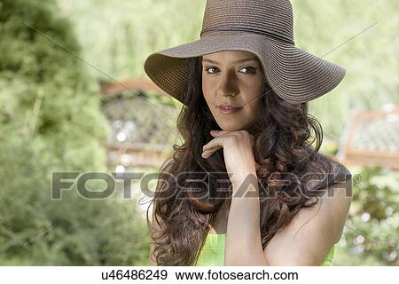 Stock Photo - Portrait of beautiful young woman wearing sunhat in park. Fotosearch
