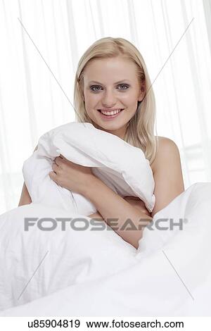 Portrait of beautiful young woman covering herself with bedsheet in bed View Large Photo Image Stock Photo - Portrait of beautiful young woman covering herself with bedsheet in bed. Fotosearch