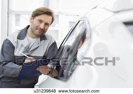 Portrait of confident automobile mechanic holding clipboard while leaning on car's window in workshop View Large Photo Image Stock Photo - Portrait of confident automobile mechanic holding clipboard while leaning on car's window in workshop. Fotosearch