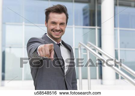 Portrait of confident businessman pointing at you outside office building View Large Photo Image Stock Photograph - Portrait of confident businessman pointing at you outside office building. Fotosearch