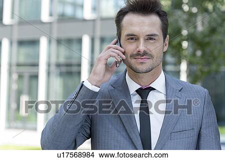 Portrait of confident businessman using cell phone outside office View Large Photo Image Picture - Portrait of confident businessman using cell phone outside office. Fotosearch