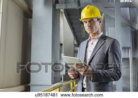 Stock Image - Portrait of confident male architect holding digital tablet in industry. Fotosearch