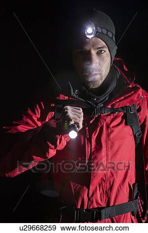 Stock Photo - Portrait of confident male hiker with flashlight at night. Fotosearch