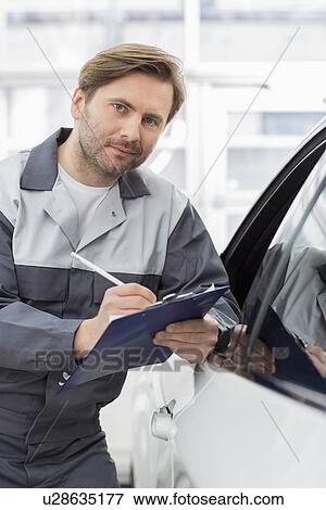 Portrait of confident mechanic holding clipboard while leaning on car's window in workshop View Large Photo Image Stock Photo - Portrait of confident mechanic holding clipboard while leaning on car's window in workshop. Fotosearch