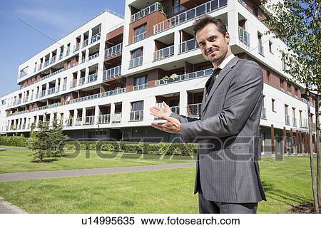 Portrait of confident real estate agent showing office building View Large Photo Image Stock Photography - Portrait of confident real estate agent showing office building. Fotosearch