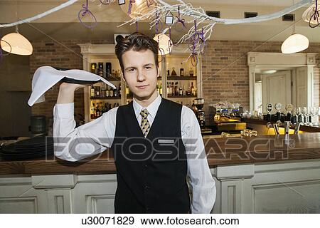 Stock Photo - Portrait of confident waiter carrying serving tray in restaurant. Fotosearch