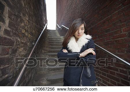 Stock Photograph - Portrait of confident woman with arms crossed standing against steps at London, England, UK. Fotosearch