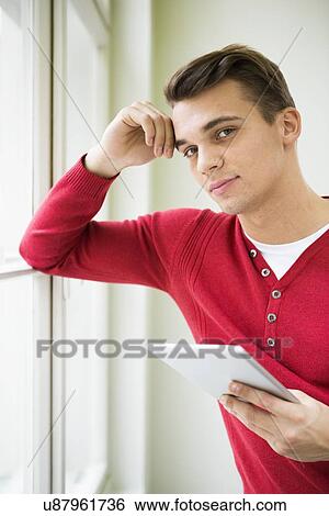 Portrait of confident young businessman holding tablet PC in office View Large Photo Image Stock Photograph - Portrait of confident young businessman holding tablet PC in office. Fotosearch
