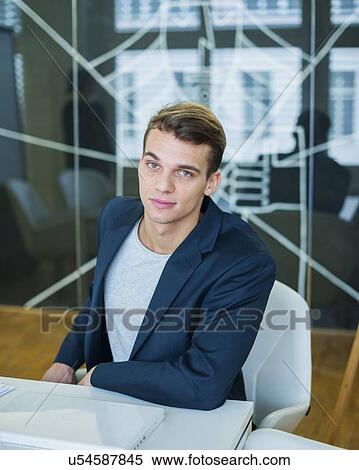 Portrait of confident young businessman sitting at conference table View Large Photo Image Stock Photography - Portrait of confident young businessman sitting at conference table. Fotosearch