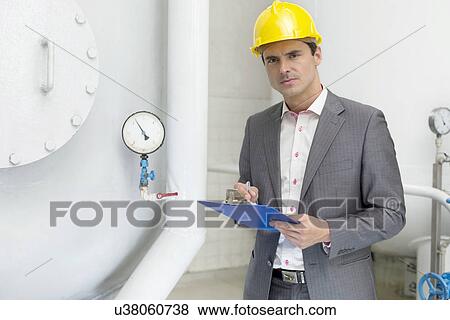 Portrait of confident young male inspector writing on clipboard in industry View Large Photo Image Stock Photo - Portrait of confident young male inspector writing on clipboard in industry. Fotosearch