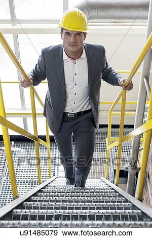 Portrait of confident young male architect walking up stairs in industry View Large Photo Image Stock Photo - Portrait of confident young male architect walking up stairs in industry. Fotosearch