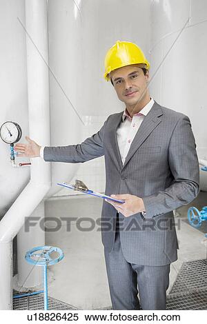 Portrait of confident young male manager with clipboard showing machine in industry View Large Photo Image Stock Photography - Portrait of confident young male manager with clipboard showing machine in industry. Fotosearch
