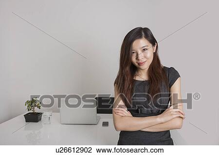 Portrait of confident young businesswoman standing arms crossed in office View Large Photo Image Stock Image - Portrait of confident young businesswoman standing arms crossed in office. Fotosearch