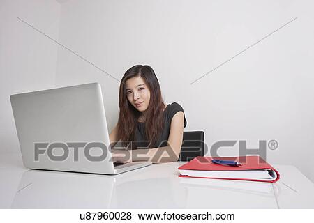 Portrait of confident young businesswoman using laptop in office View Large Photo Image Stock Photo - Portrait of confident young businesswoman using laptop in office. Fotosearch