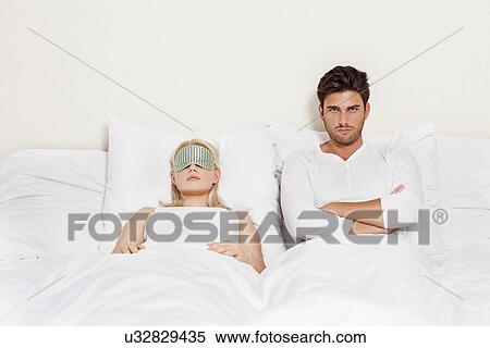 Portrait of displeased man with woman sleeping in bed View Large Photo Image Stock Photography - Portrait of displeased man with woman sleeping in bed. Fotosearch