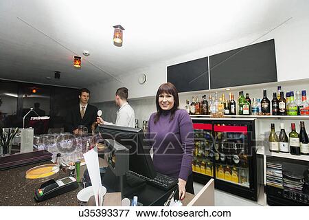 Stock Photo - Portrait of female cashier with manager and bartender at bar counter. Fotosearch