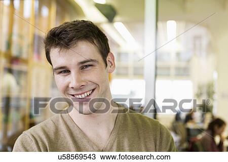 Portrait of handsome young businessman smiling in office View Large Photo Image Stock Image - Portrait of handsome young businessman smiling in office. Fotosearch