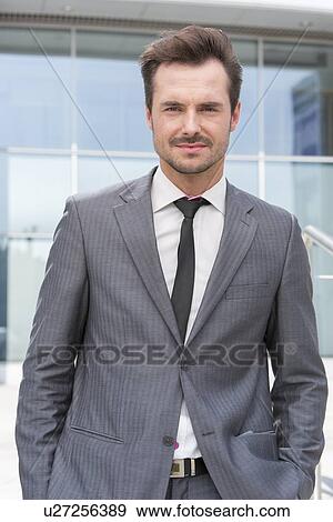 Portrait of handsome young businessman standing outside office building View Large Photo Image Stock Photo - Portrait of handsome young businessman standing outside office building. Fotosearch