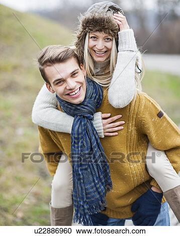 Portrait of happy man piggybacking woman in park View Large Photo Image Stock Image - Portrait of happy man piggybacking woman in park. Fotosearch