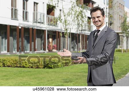 Portrait of happy real estate agent presenting office building View Large Photo Image Stock Photo - Portrait of happy real estate agent presenting office building. Fotosearch