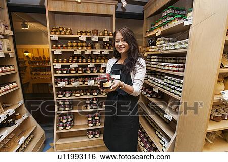 Portrait of happy saleswoman showing product in grocery store View Large Photo Image Stock Photograph - Portrait of happy saleswoman showing product in grocery store. Fotosearch