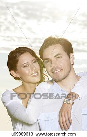 Portrait of happy woman with arm around man at beach View Large Photo Image Stock Image - Portrait of happy woman with arm around man at beach. Fotosearch