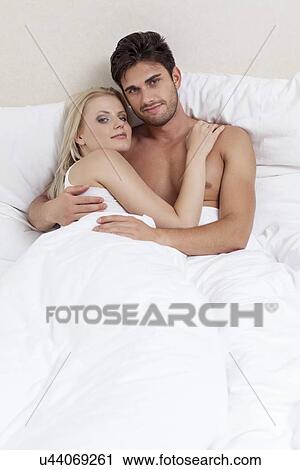 Stock Image - Portrait of happy young couple spending quality time in bed. Fotosearch