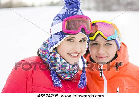 Stock Photography - Portrait of happy young female friends in warm clothing outdoors. Fotosearch