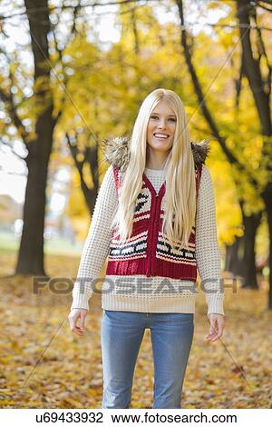 Portrait of happy young woman standing in park during autumn View Large Photo Image Stock Image - Portrait of happy young woman standing in park during autumn. Fotosearch