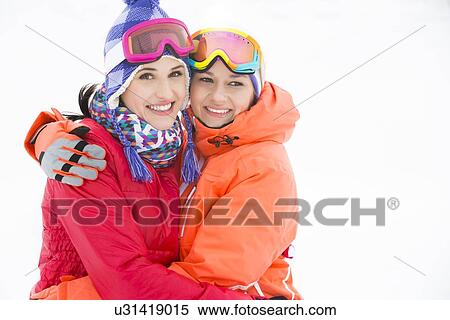 Stock Photography - Portrait of happy young women in warm clothing embracing outdoors. Fotosearch