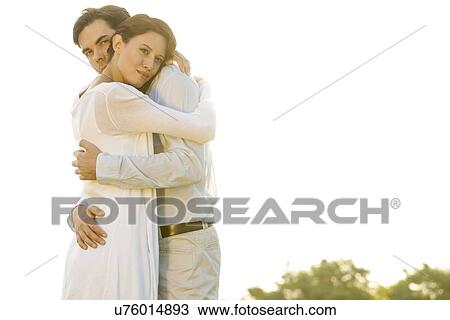Portrait of loving man embracing woman in park against clear sky View Large Photo Image Stock Image - Portrait of loving man embracing woman in park against clear sky. Fotosearch
