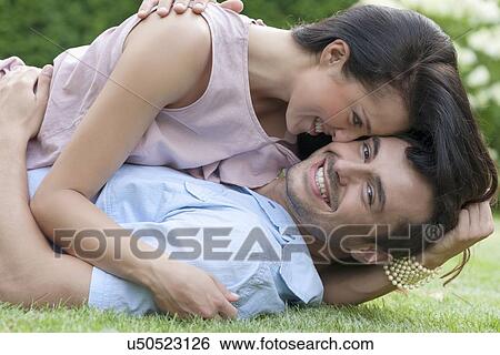 Portrait of loving young couple enjoying together in park View Large Photo Image Stock Photograph - Portrait of loving young couple enjoying together in park. Fotosearch