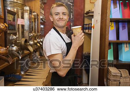 Portrait of male salesperson holding disposable coffee cup in store View Large Photo Image Stock Photograph - Portrait of male salesperson holding disposable coffee cup in store. Fotosearch