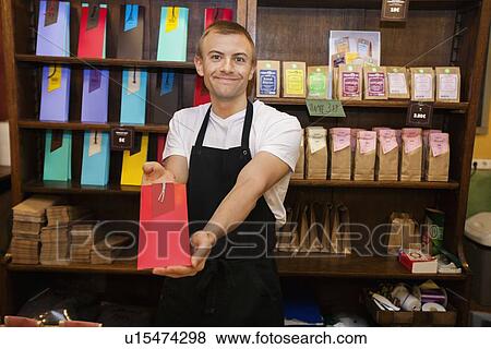 Portrait of male salesperson showing product in coffee store View Large Photo Image Stock Photo - Portrait of male salesperson showing product in coffee store. Fotosearch