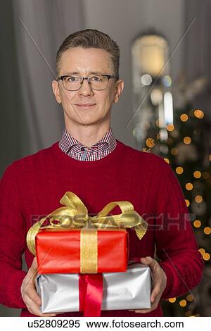 Portrait of mature man holding stack of Christmas presents View Large Photo Image Stock Photography - Portrait of mature man holding stack of Christmas presents. Fotosearch