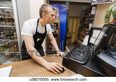 Portrait of salesman using computer at cash counter in supermarket View Large Photo Image Stock Photography - Portrait of salesman using computer at cash counter in supermarket. Fotosearch