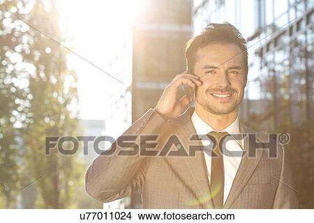 Portrait of smiling businessman using cell phone outdoors View Large Photo Image Picture - Portrait of smiling businessman using cell phone outdoors. Fotosearch