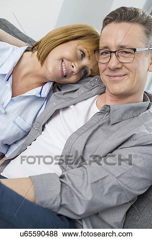 Portrait of smiling man sitting with woman at home View Large Photo Image Stock Photo - Portrait of smiling man sitting with woman at home. Fotosearch