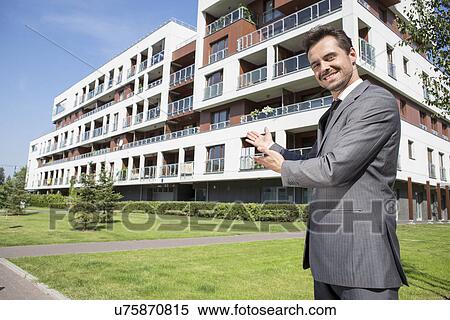 Portrait of smiling real estate agent presenting office building View Large Photo Image Stock Photography - Portrait of smiling real estate agent presenting office building. Fotosearch