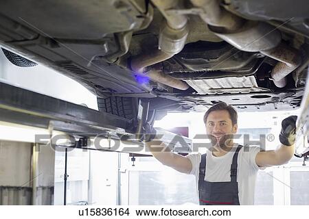 Portrait of smiling repair worker examining car in workshop View Large Photo Image Picture - Portrait of smiling repair worker examining car in workshop. Fotosearch