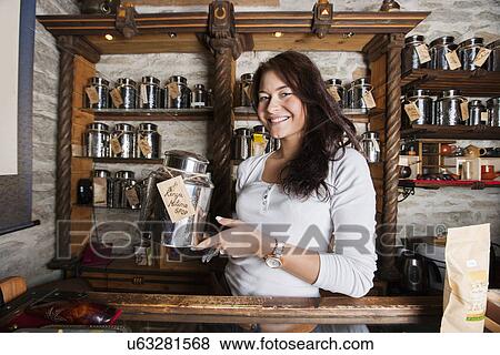 Stock Photo - Portrait of smiling salesperson displaying tea container in store. Fotosearch